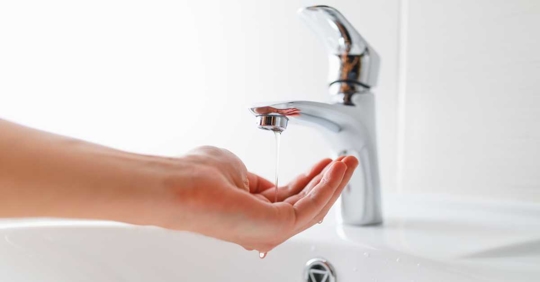 hand under faucet with low pressure water stream